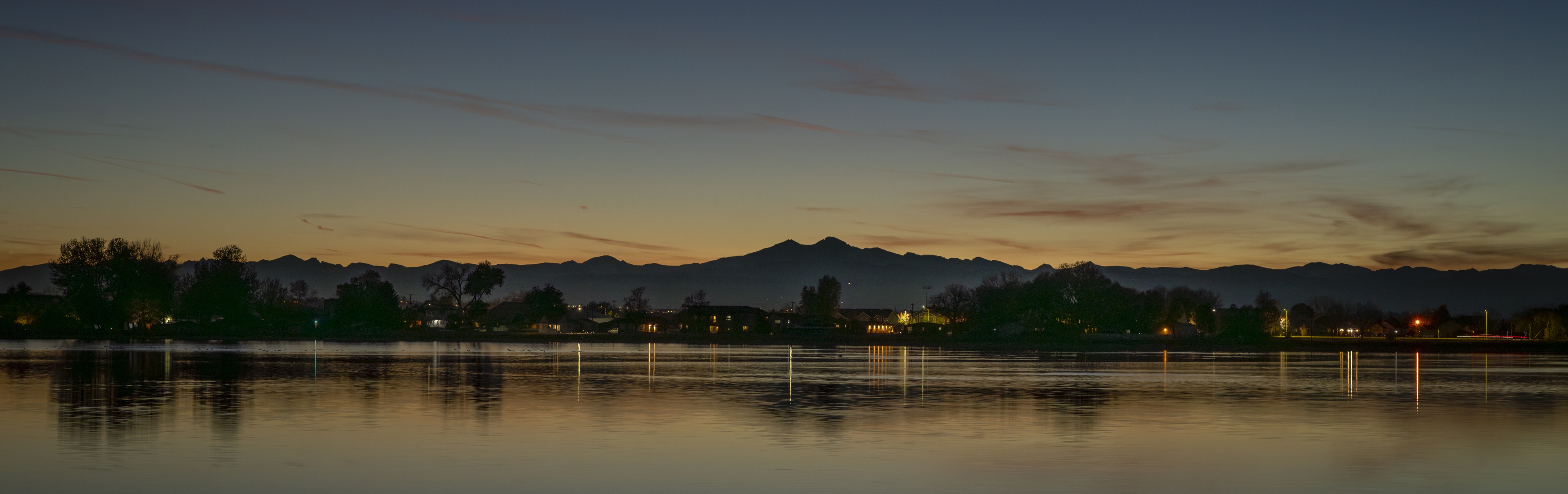 A body of water with trees and mountains in the background.