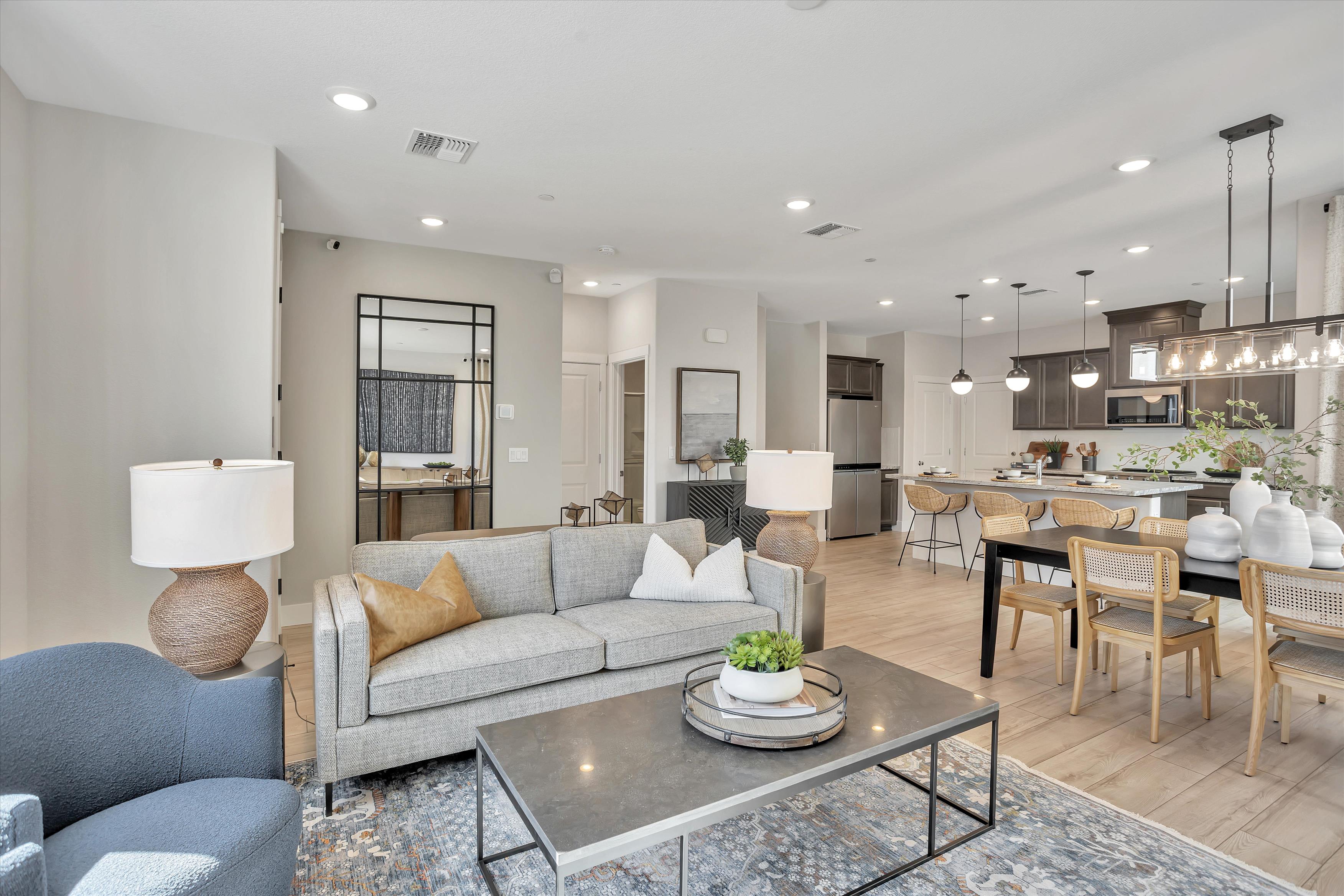 A living room with a large dining table and a large kitchen.