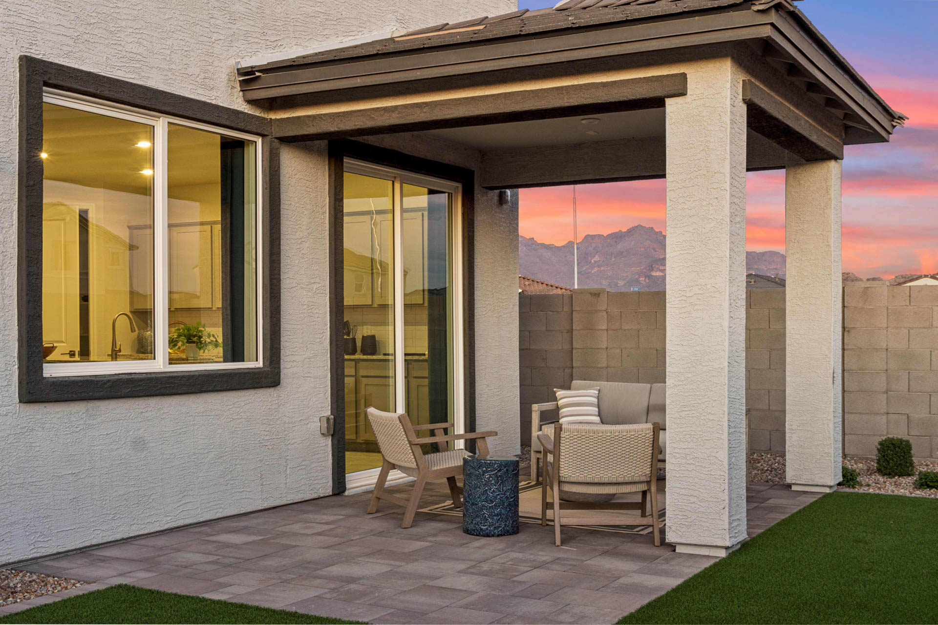 A patio with a table chairs and a window with a view of mountains.