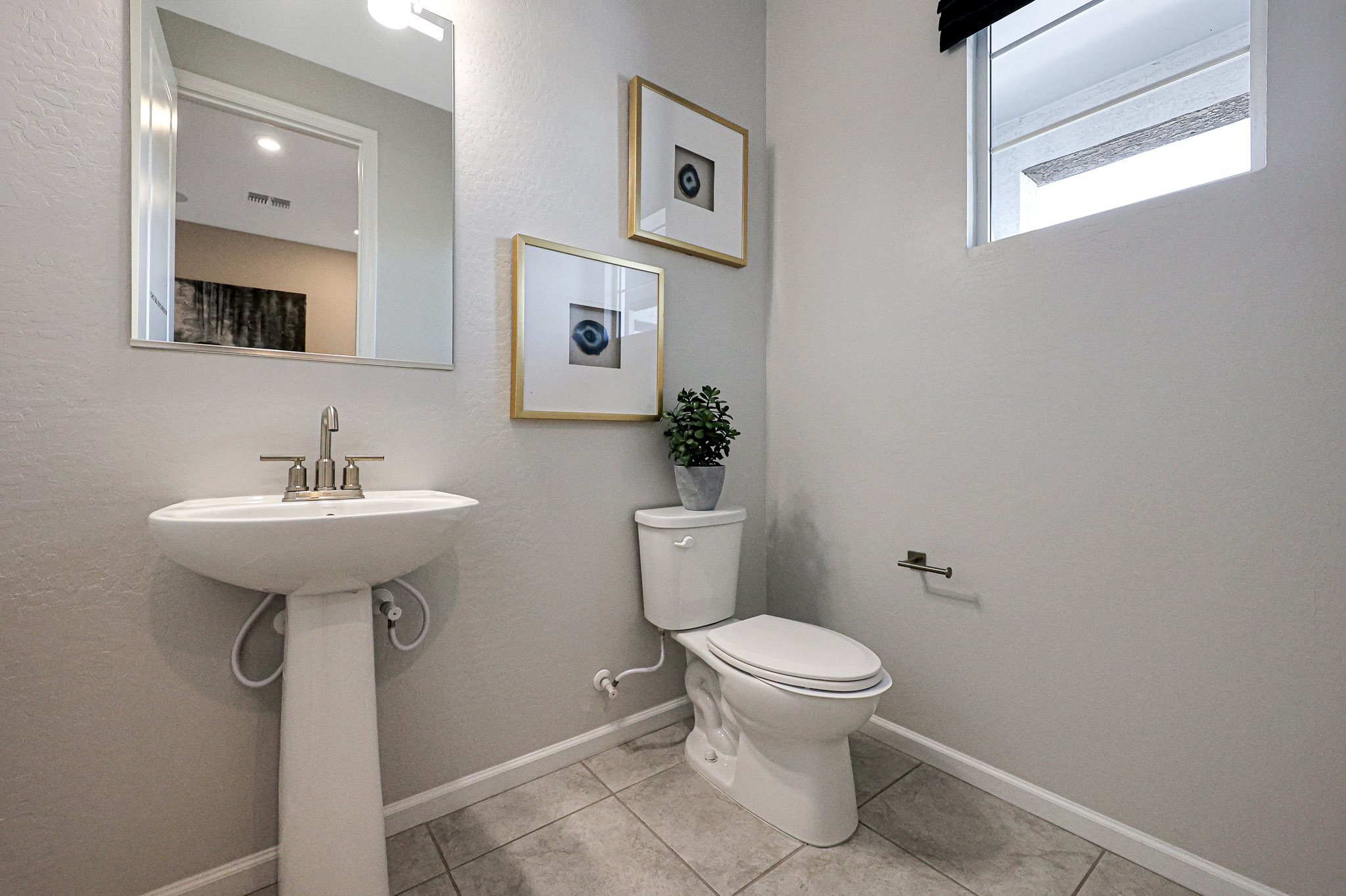 A bathroom with a sink toilet and mirror.