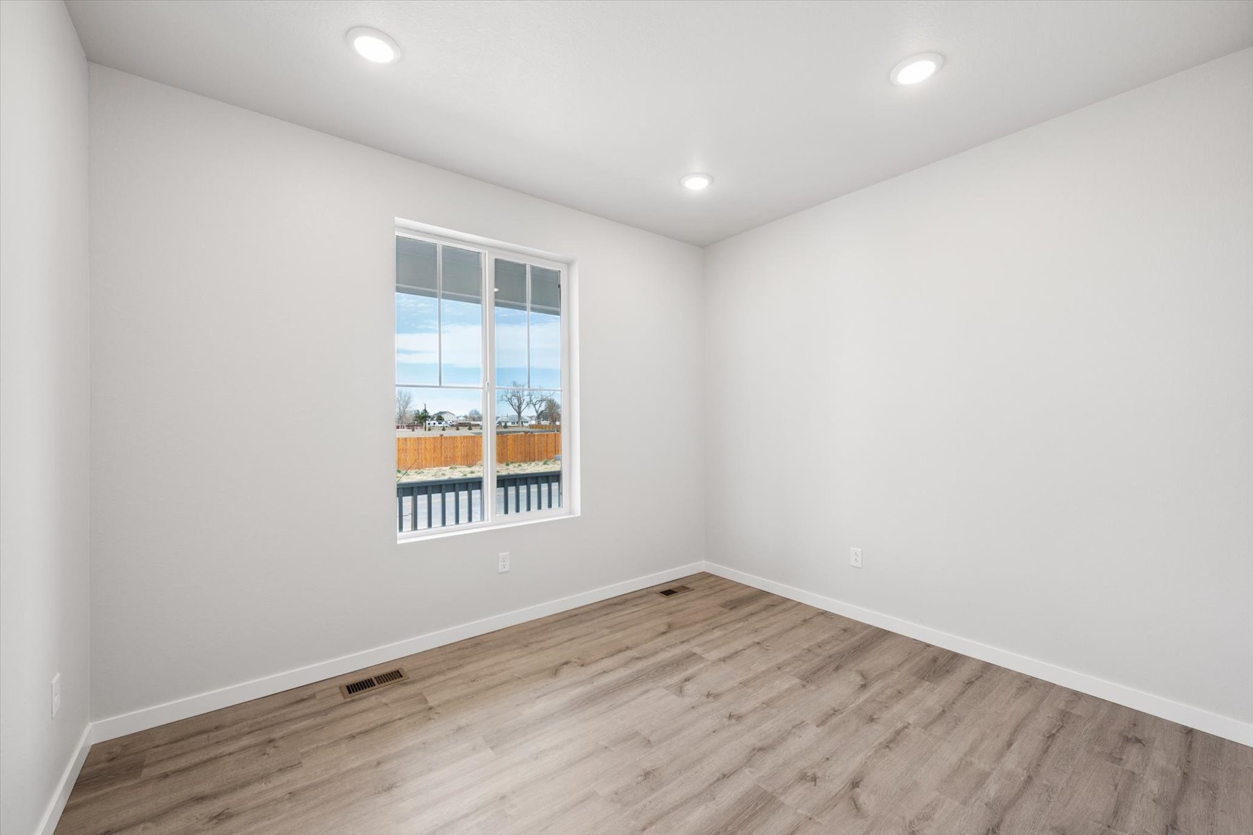 A room with a window and a wood floor.