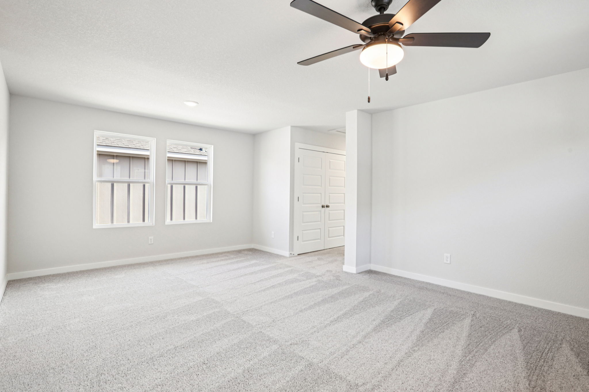 A room with a ceiling fan and white cabinets.