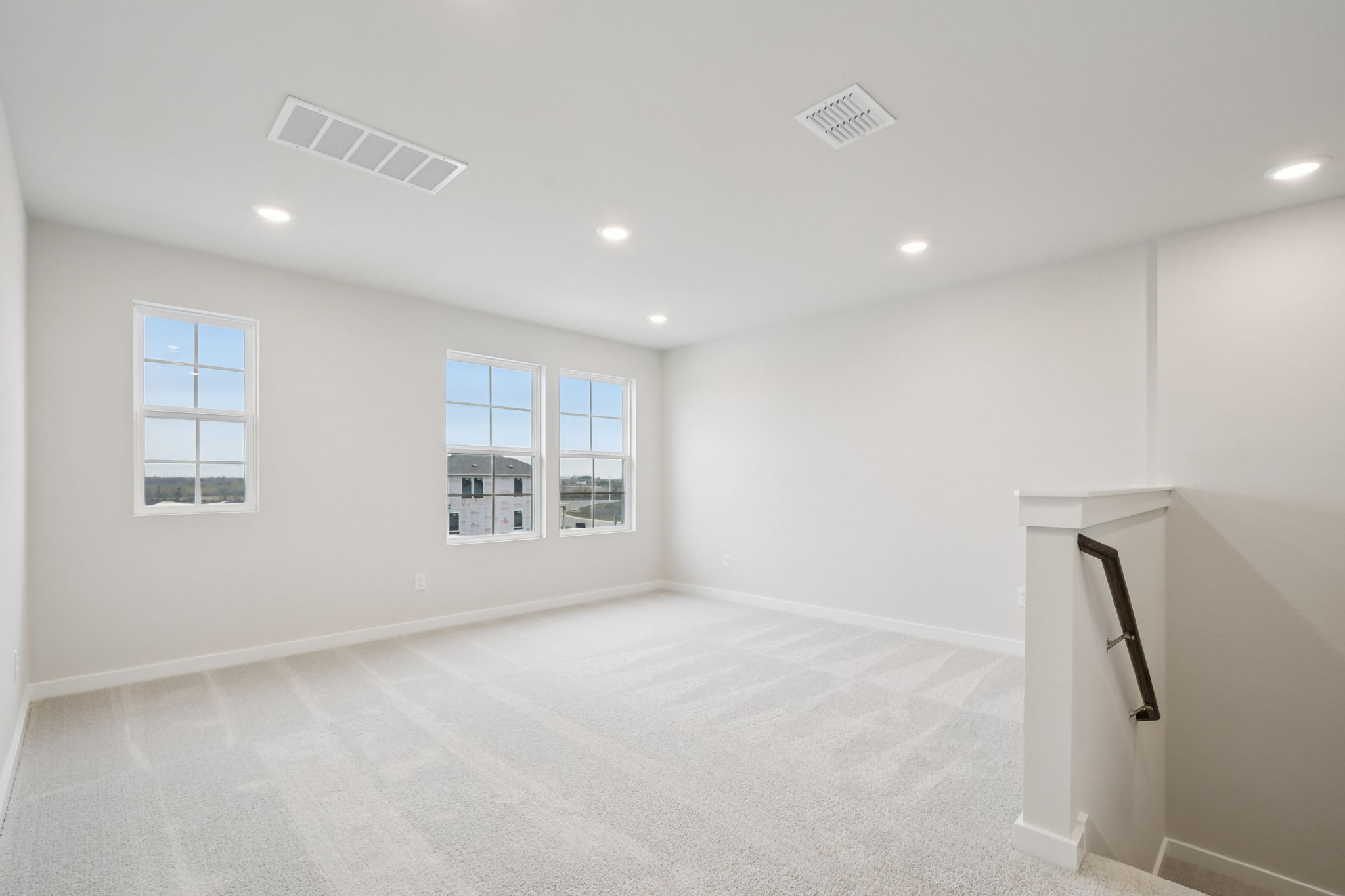 A room with a white carpet and windows.