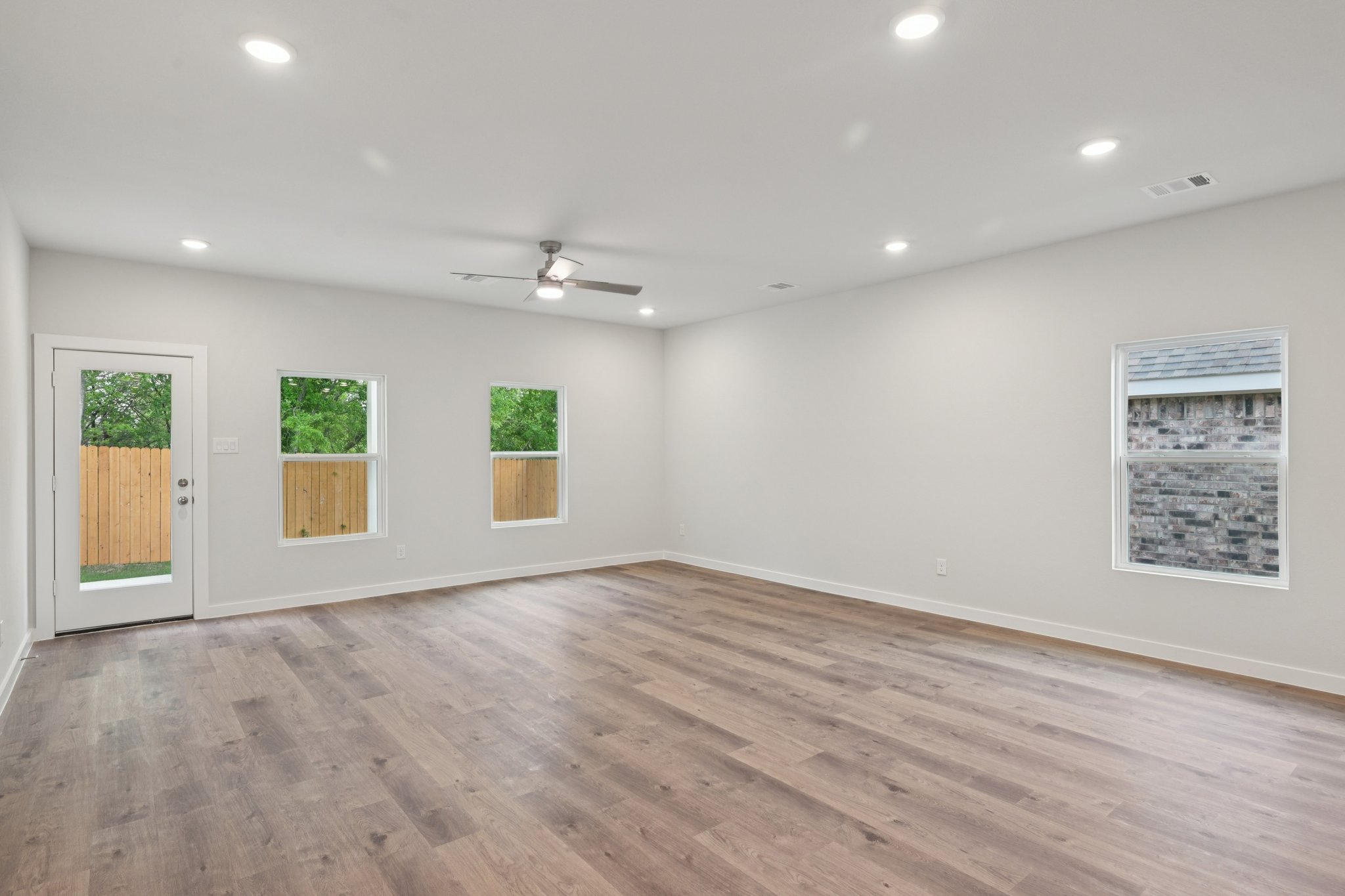 A room with a wood floor and a ceiling fan and a wood floor.