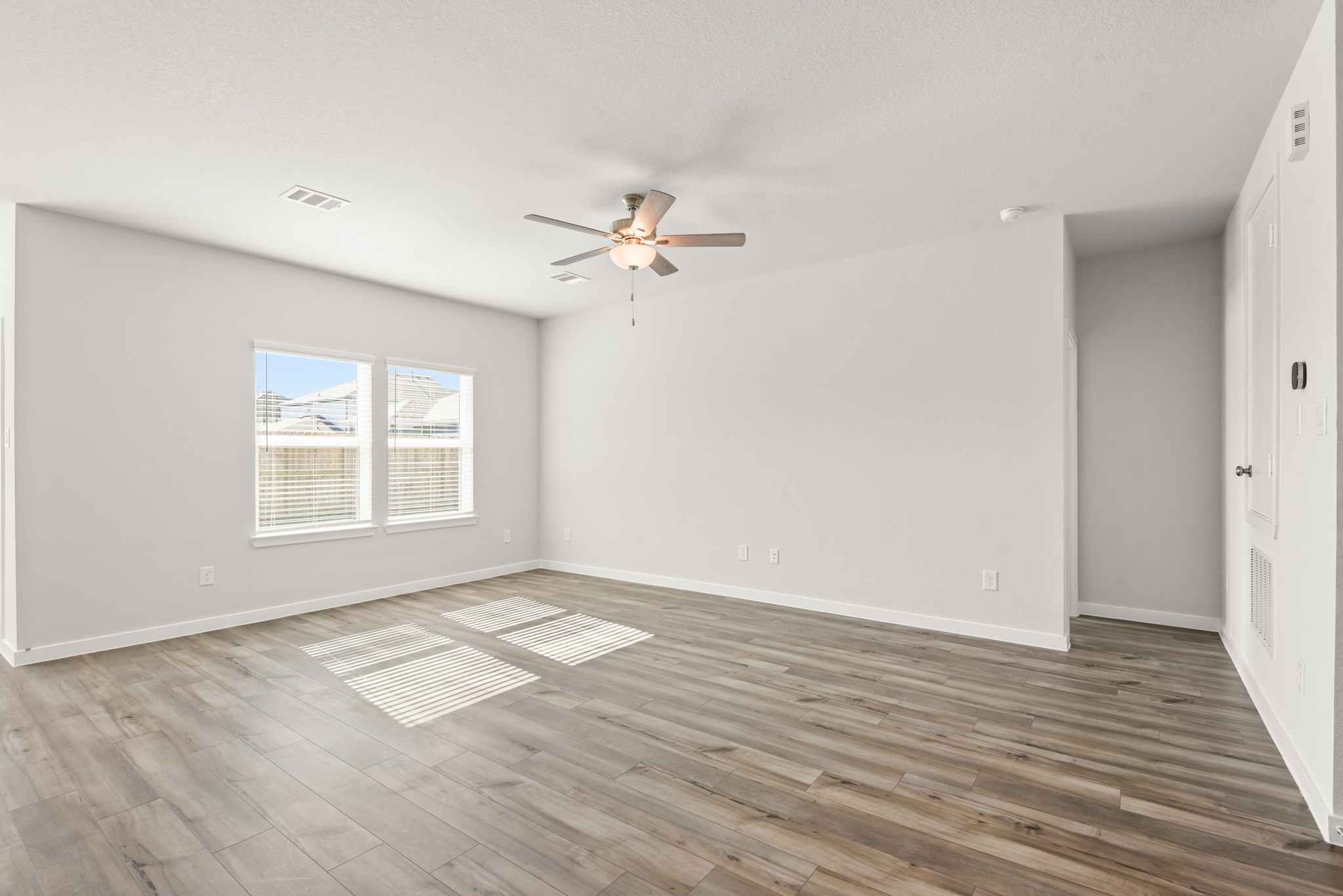 A room with a wood floor and a ceiling fan.