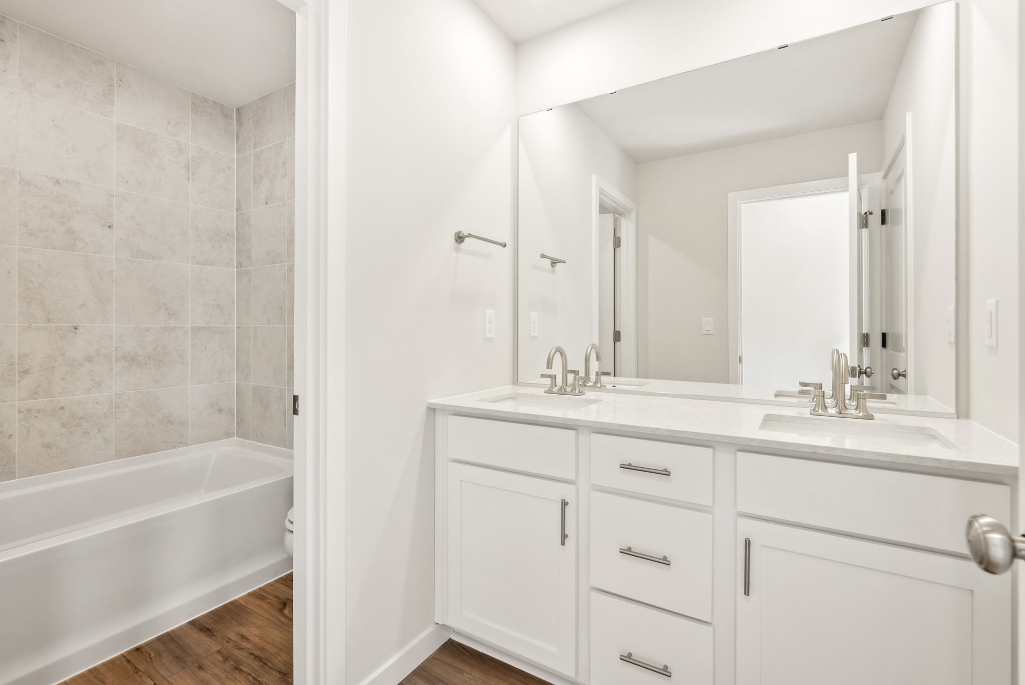 A bathroom with a tub sink and mirror.