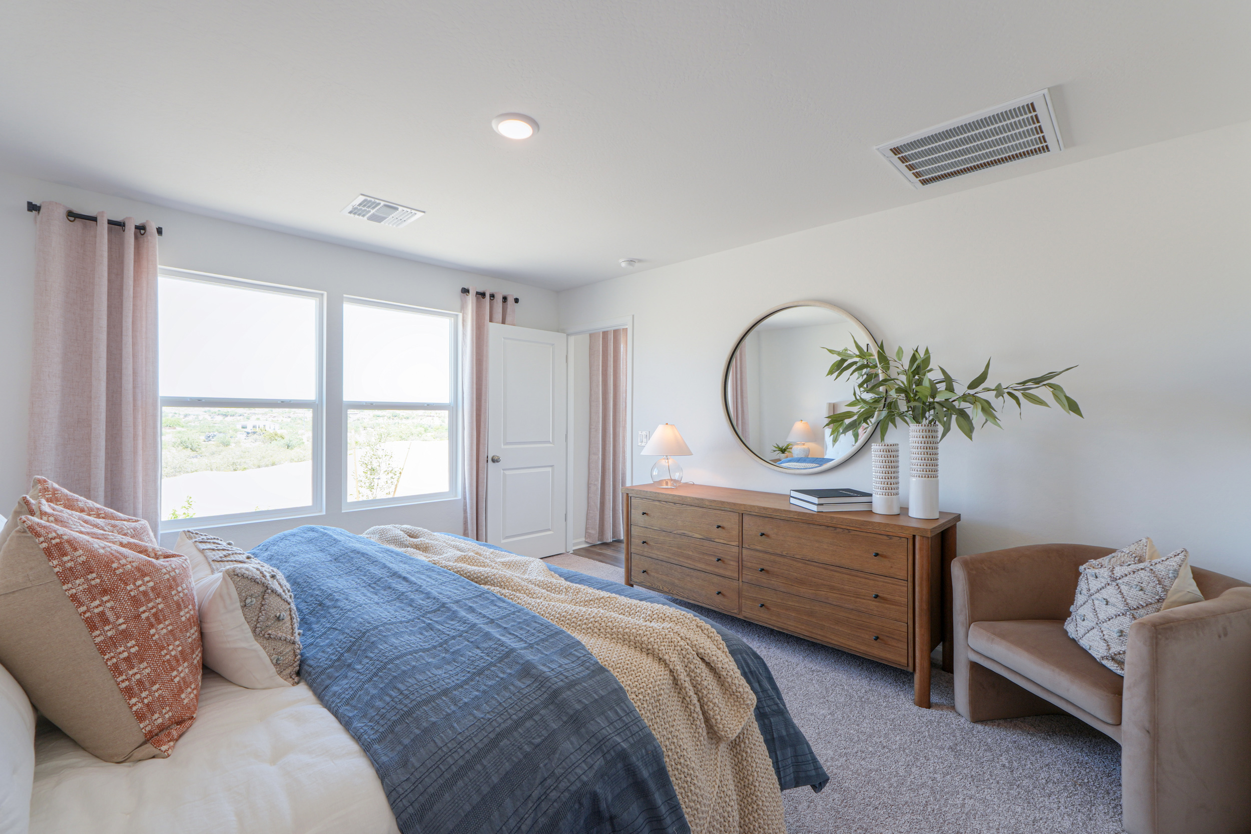 A bedroom with a bed and a mirror.